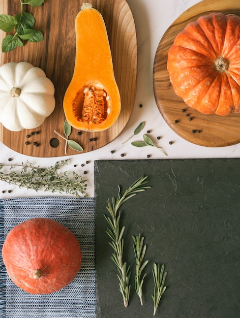 Zucche di vari colori e forme su varie assi e tessuti e una lavagna di ardesia