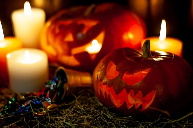 Zucche e candele d'ardore di Halloween su una tabella con una paglia