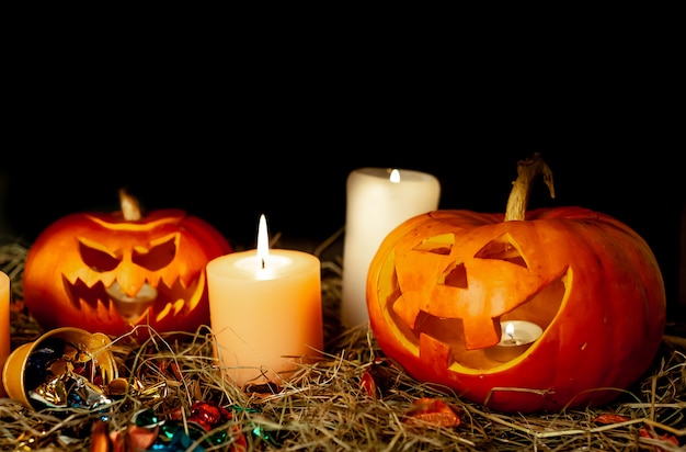 Zucche e candele d'ardore di Halloween su una tabella con una paglia