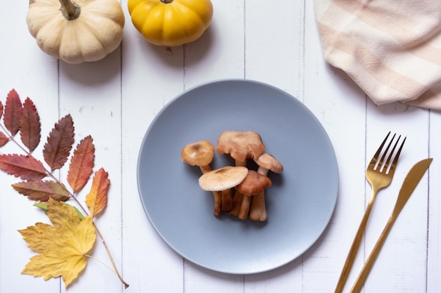 Zucche e funghi su un piatto con posate su sfondo di legno piatto vista dall'alto