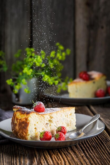 Zucchero a velo in caduta su cheesecake con fragole fresche