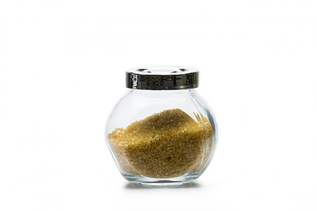 Zucchero bruno in bottiglia di vetro isolata su fondo bianco