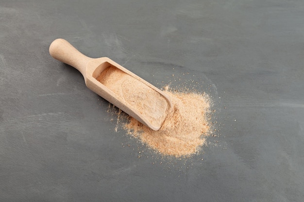 Zucchero di datteri in paletta di legno Senza zuccheri raffinati Polvere di datteri naturale sparsa sulla superficie grigia