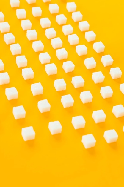 Zucchero raffinato su sfondo giallo Cubetti di zucchero dolce e bianco a forma geometrica Ombre dure