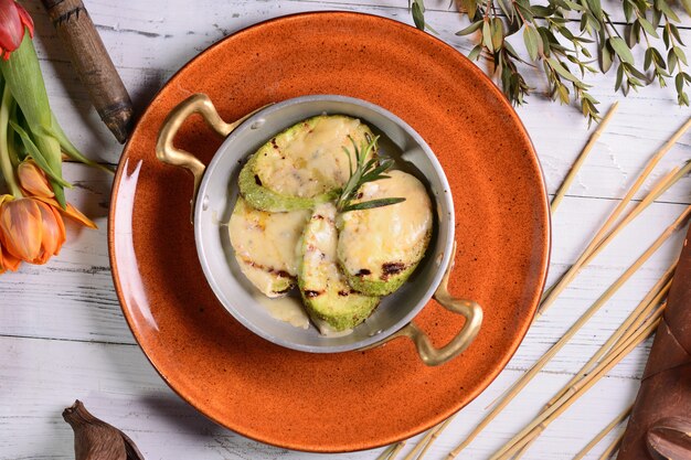 Zucchine al forno con formaggio al rosmarino. In un piatto rosso