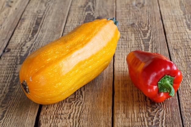 Zucchine appena raccolte e peperone rosso su vecchie tavole di legno. Verdure appena raccolte.