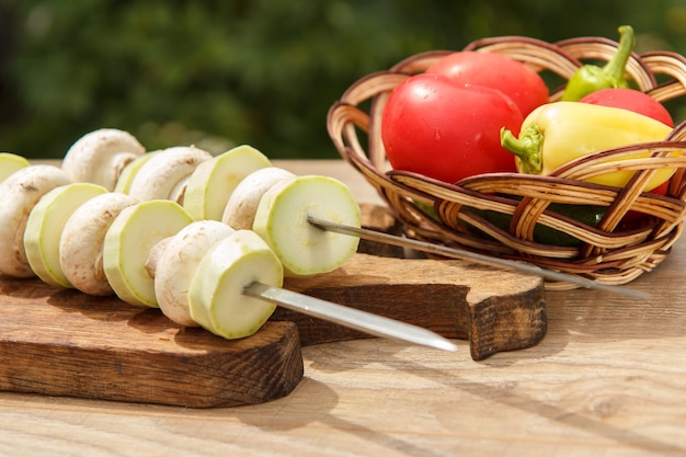 Zucchine e funghi su spiedini con pomodori cetrioli e peperoni in un cesto di vimini