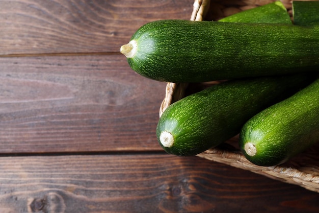 Zucchine fresche in cesto di vimini su sfondo di legno