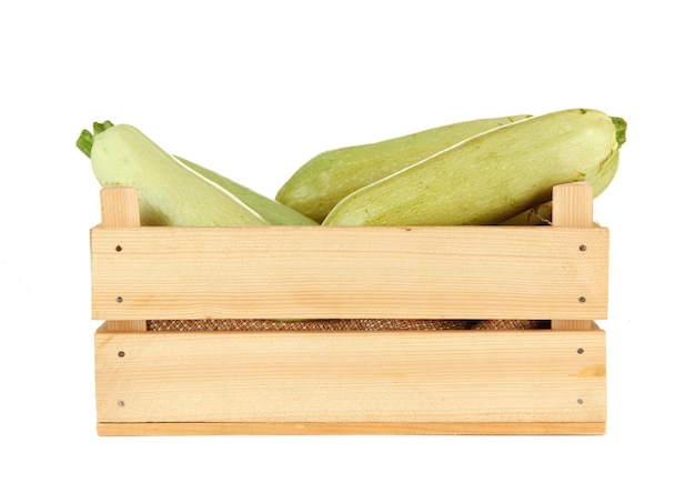 Zucchine fresche in scatola di legno isolata su bianco