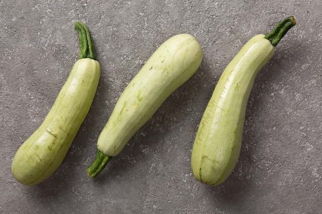 Zucchine fresche su uno sfondo di cemento grigio.