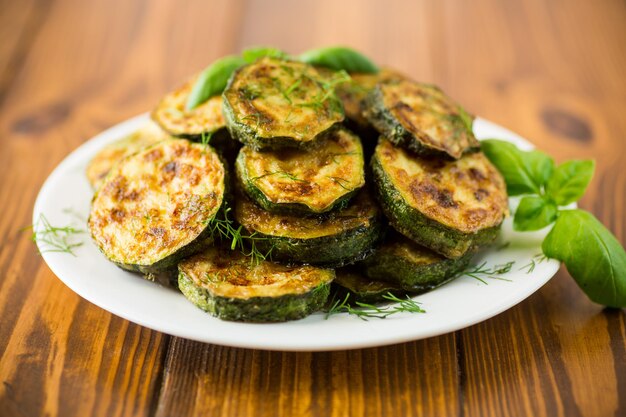 zucchine fritte in cerchi con spezie ed erbe aromatiche in un piatto su un tavolo di legno