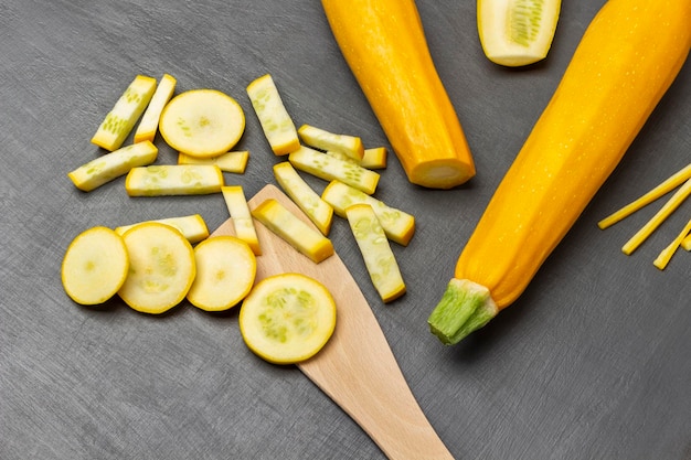 Zucchine gialle a fette e una spatola di legno Zucchine intere