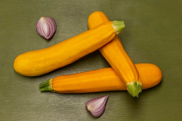 Zucchine gialle e metà cipolla blu su sfondo verde