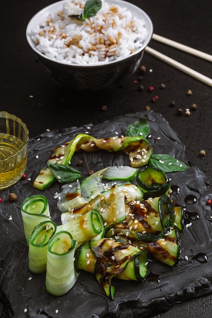 Zucchine grigliate con salsa e cetriolo su un tavolo nero