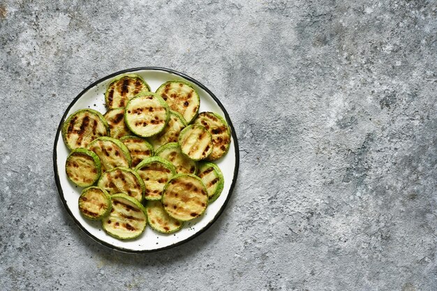 Zucchine grigliate con salsa su fondo di cemento. Vista dall'alto.