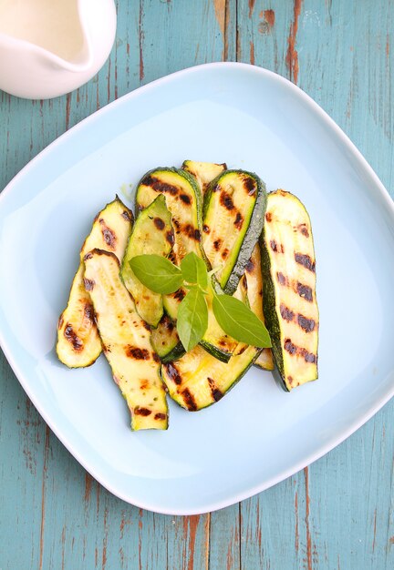 Zucchine grigliate su un piatto blu con basilico