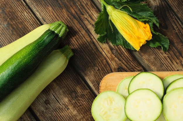 Zucchine intere organiche e affettate sulla tavola di legno.