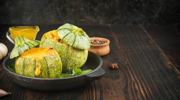 Zucchine ripiene di formaggio su un tavolo scuro. Vista laterale. Copia spazio.