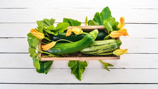 Zucchine verdi in una scatola di legno Verdure fresche su uno sfondo di legno bianco Vista dall'alto Spazio di copia