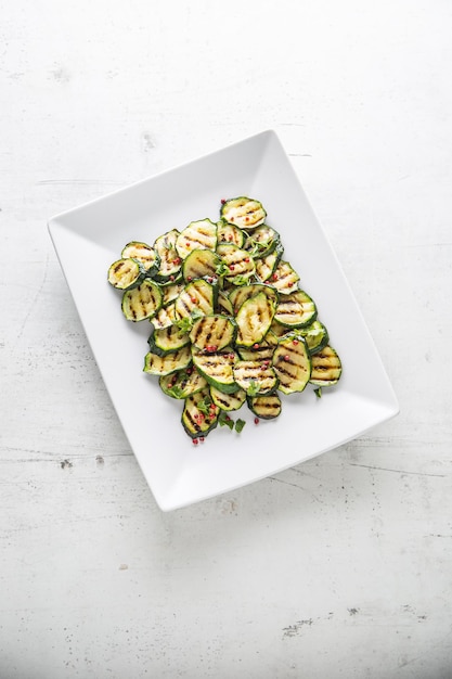 Zucchine. Zucchine grigliate con spezie rosse su piatto bianco.