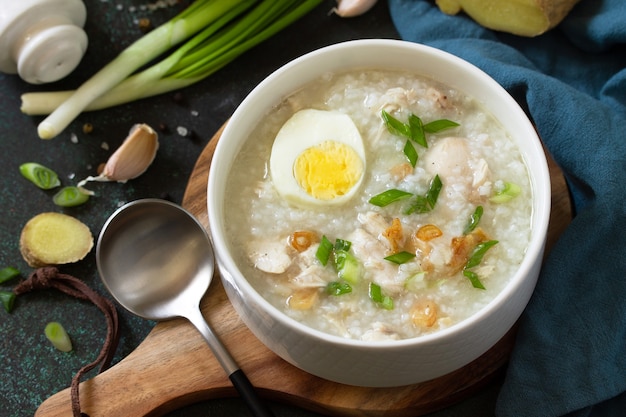 Zuppa Arroz Caldo Zuppa calda con riso pollo allo zenzero e aglio in una ciotola su un piano di lavoro scuro