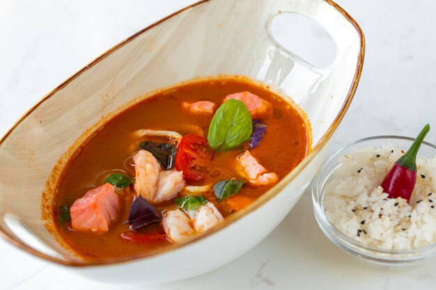 Zuppa asiatica di tom yum in una ciotola sul tavolo grigio