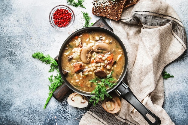 Zuppa calda di funghi vegetali di carne autunnale o invernale con manzo e orzo integrale Con breav nero e prezzemolo vista dall'alto tavolo da cucina grigio spazio copia