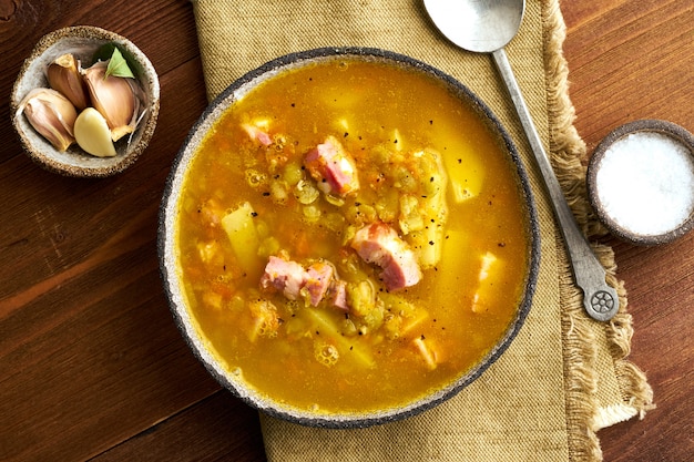 Zuppa calda invernale con piselli tritati, carne di maiale, pancetta affumicata, affumicato sul tavolo di legno marrone scuro