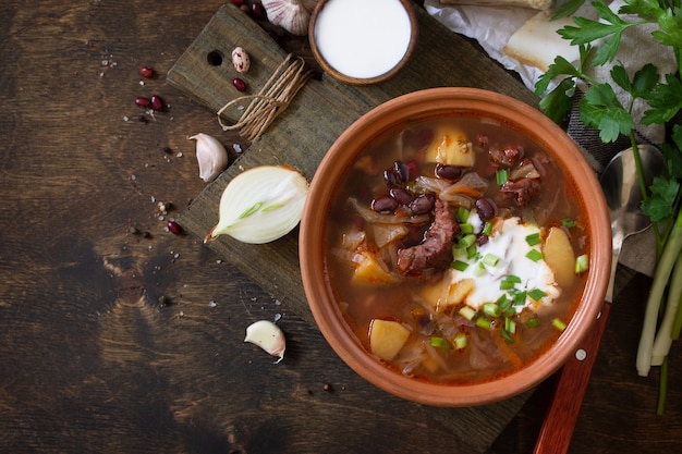 Zuppa con carne e fagioli o Borsch servito con panna acida Vista dall'alto flat lay Spazio copia