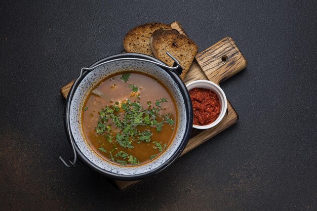 Zuppa con carne e verdure in una pentola su uno sfondo scuro