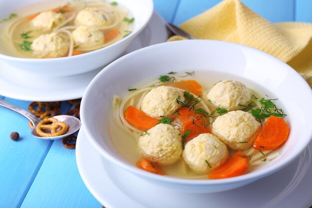 Zuppa con polpette e tagliatelle in ciotole su fondo di legno di colore