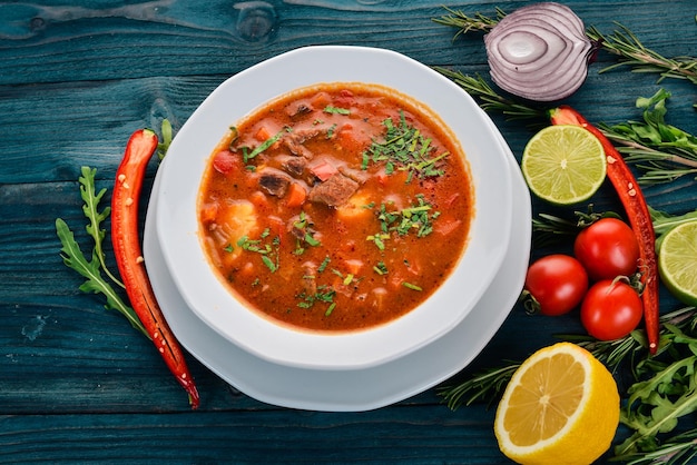 Zuppa con pomodori di manzo e verdure fresche su uno sfondo di legno Vista dall'alto Copia spazio