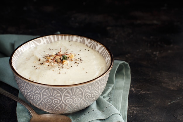 Zuppa cremosa di cavolfiore in una ciotola su sfondo scuro