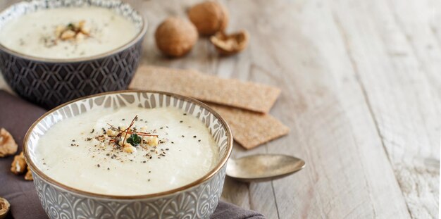 Zuppa cremosa di cavolfiore in una ciotola su un tavolo di legno