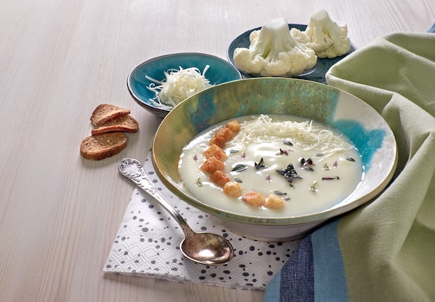 Zuppa cremosa di cavolfiore in una tazza blu con crostini di pane e parmigiano