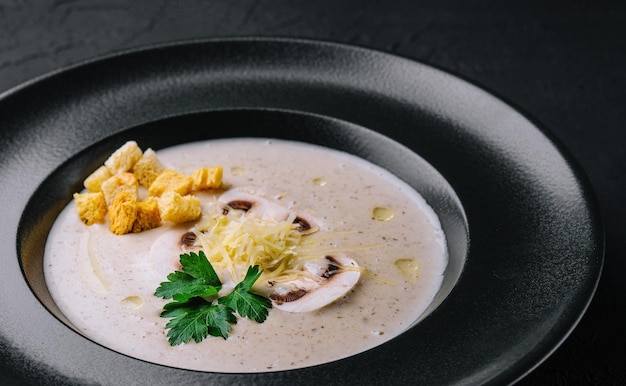 Zuppa cremosa di funghi con champignon su fondo nero