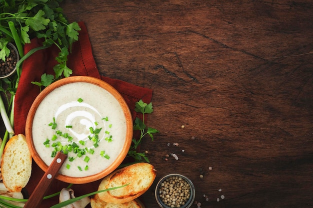 Zuppa cremosa di funghi con crostini di spezie ed erba cipollina su sfondo rustico tavolo in legno