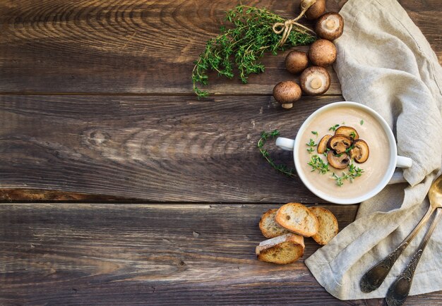 Zuppa cremosa di funghi con funghi prataioli su fondo di legno rustico. Vista dall'alto. Copia spazio.