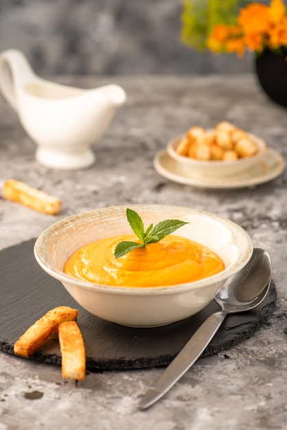 Zuppa cremosa di zucca e carote, condita con panna. Servito con crostini fritti.