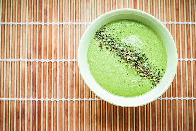 Zuppa cruda con avocado, piselli, spinaci e spezie per una dieta sana, servizio di consegna di cibo e concetto di ordine online