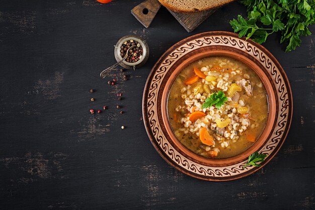 Zuppa d'orzo con carote, pomodoro, sedano e carne su un tavolo scuro