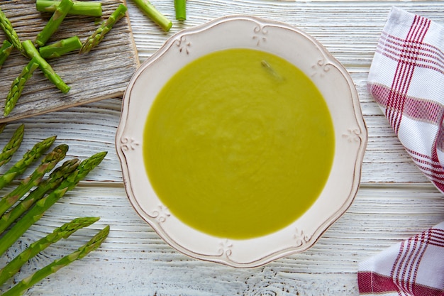 Zuppa di asparagi verde crema sul tavolo di legno bianco