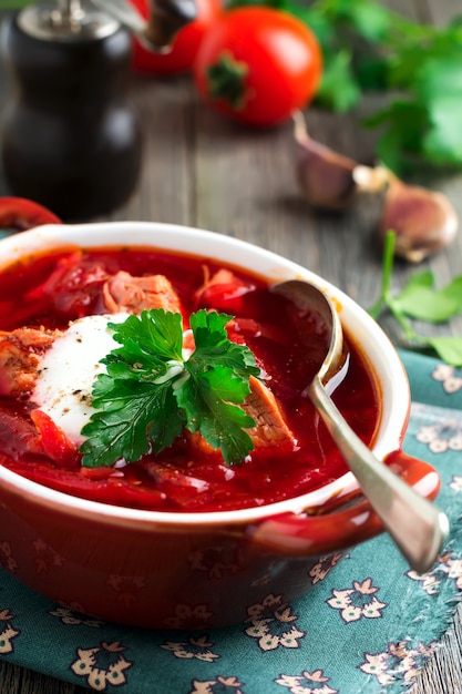 Zuppa di barbabietole con carne, panna acida e prezzemolo in una ciotola di ceramica marrone