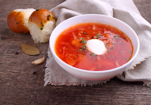 Zuppa di borsch rosso in una ciotola bianca con panna acida e prezzemolo