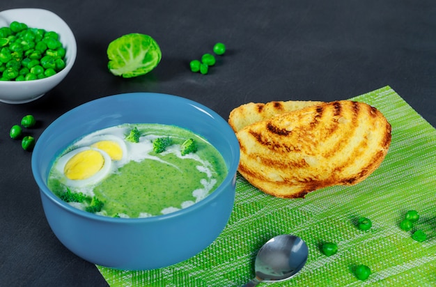 Zuppa di broccoli e pisello verde con crostini su fondo di legno