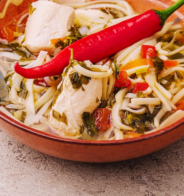 Zuppa di brodo di pollo con tagliatelle erbe pepe e verdure sul piatto
