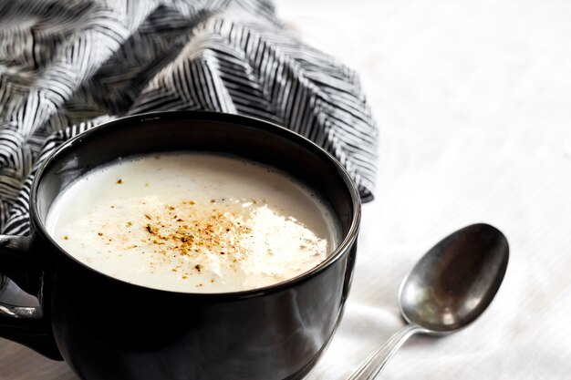 Zuppa di cavolfiore (Creme du Barry) in una ciotola nera su sfondo bianco con panno bianco e nero