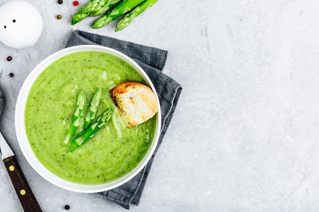 Zuppa di crema di asparagi con crostini su sfondo di pietra grigia vista dall'alto Zuppa di verdure estiva verde