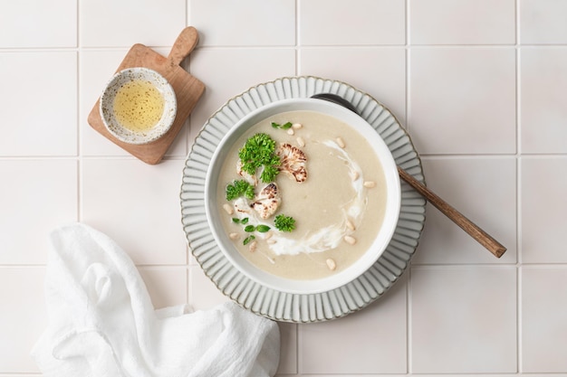 Zuppa di crema di cavolfiore con noci di pino in una ciotola su uno sfondo bianco