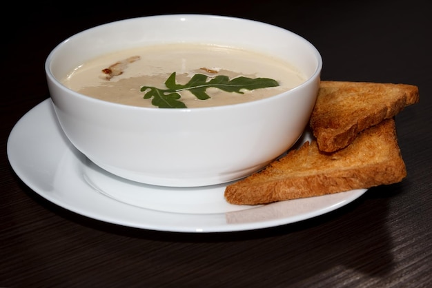 Zuppa di crema di formaggio con crostini ciotola bianca fondo di legno scuro